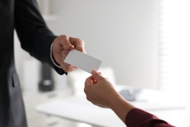 Man giving business card to woman in office, closeup. Mockup for design