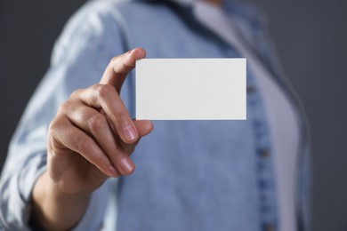 Woman holding blank business card on grey background, closeup. Mockup for design