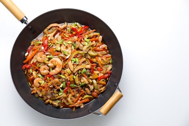 Stir-fry sea food in wok on white background, top view. Space for text