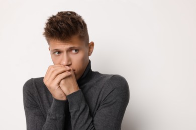 Photo of Portrait of scared young man on light background, space for text