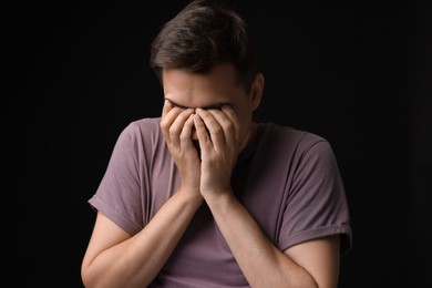 Portrait of scared young man on black background