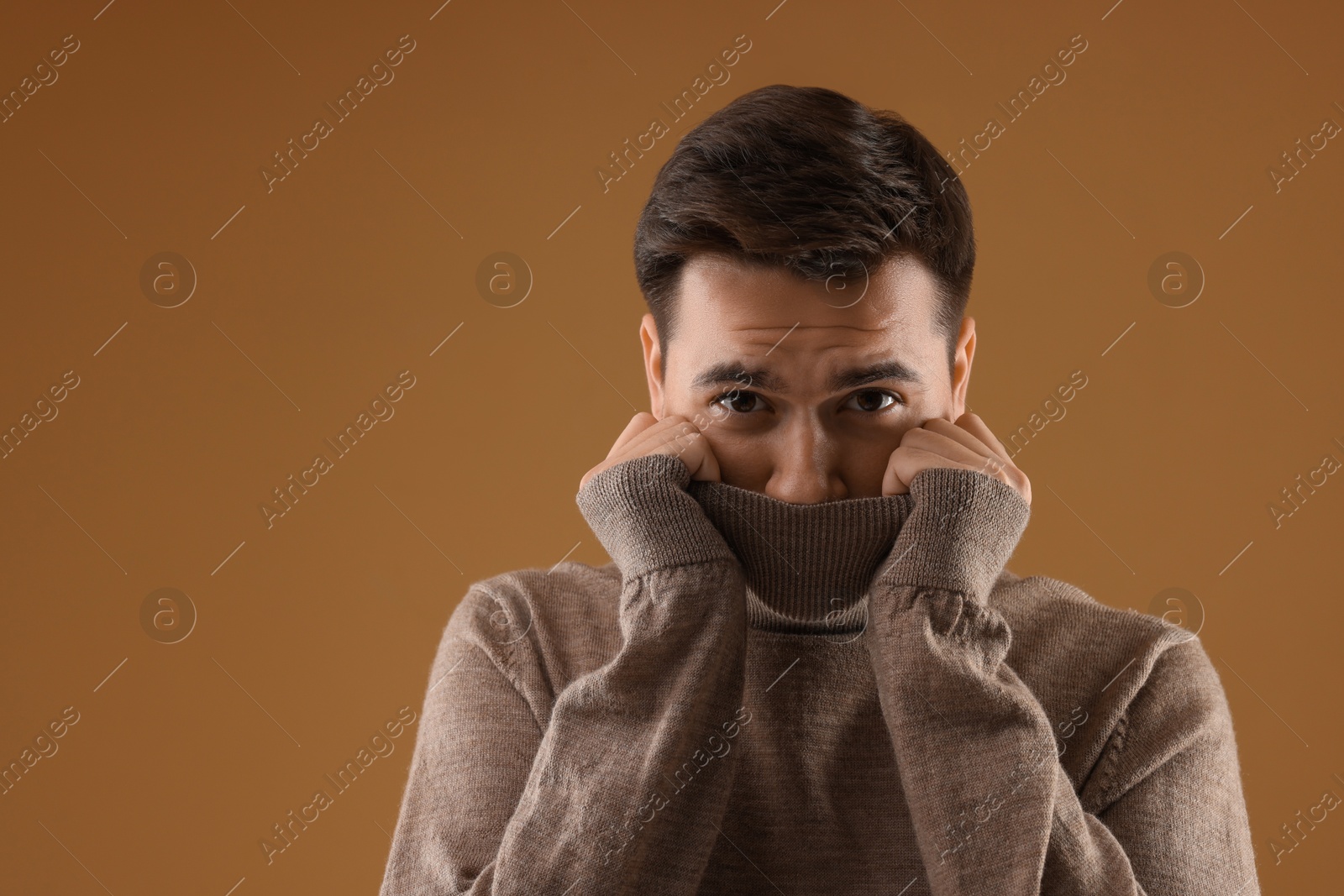 Photo of Portrait of scared young man on brown background, space for text