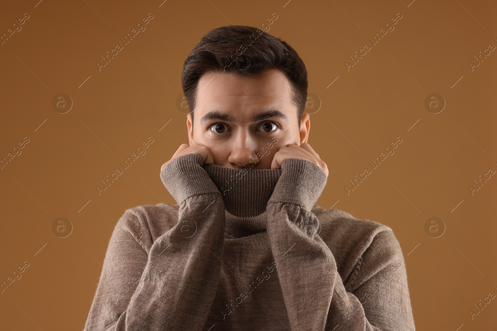 Photo of Portrait of scared young man on brown background