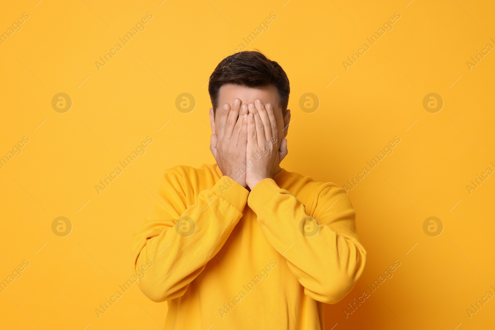 Photo of Portrait of scared young man on orange background