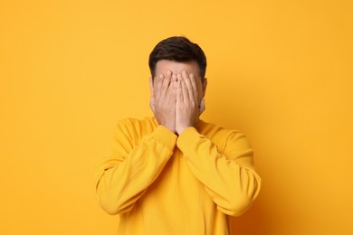 Portrait of scared young man on orange background