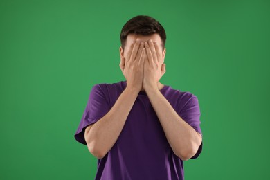 Portrait of scared young man on green background