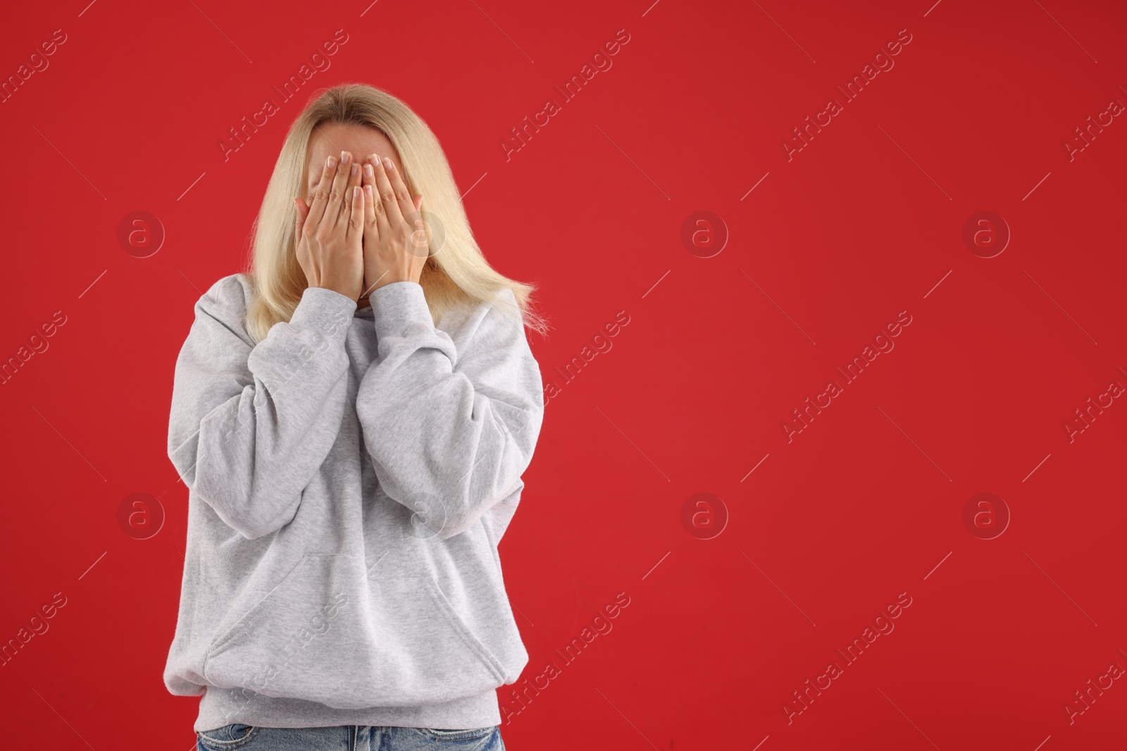 Photo of Portrait of scared woman on red background, space for text