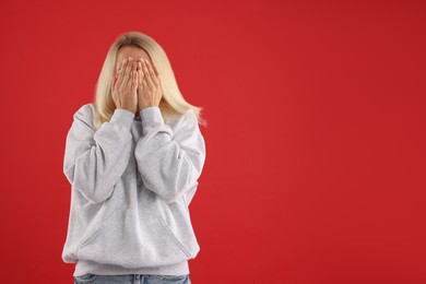 Photo of Portrait of scared woman on red background, space for text