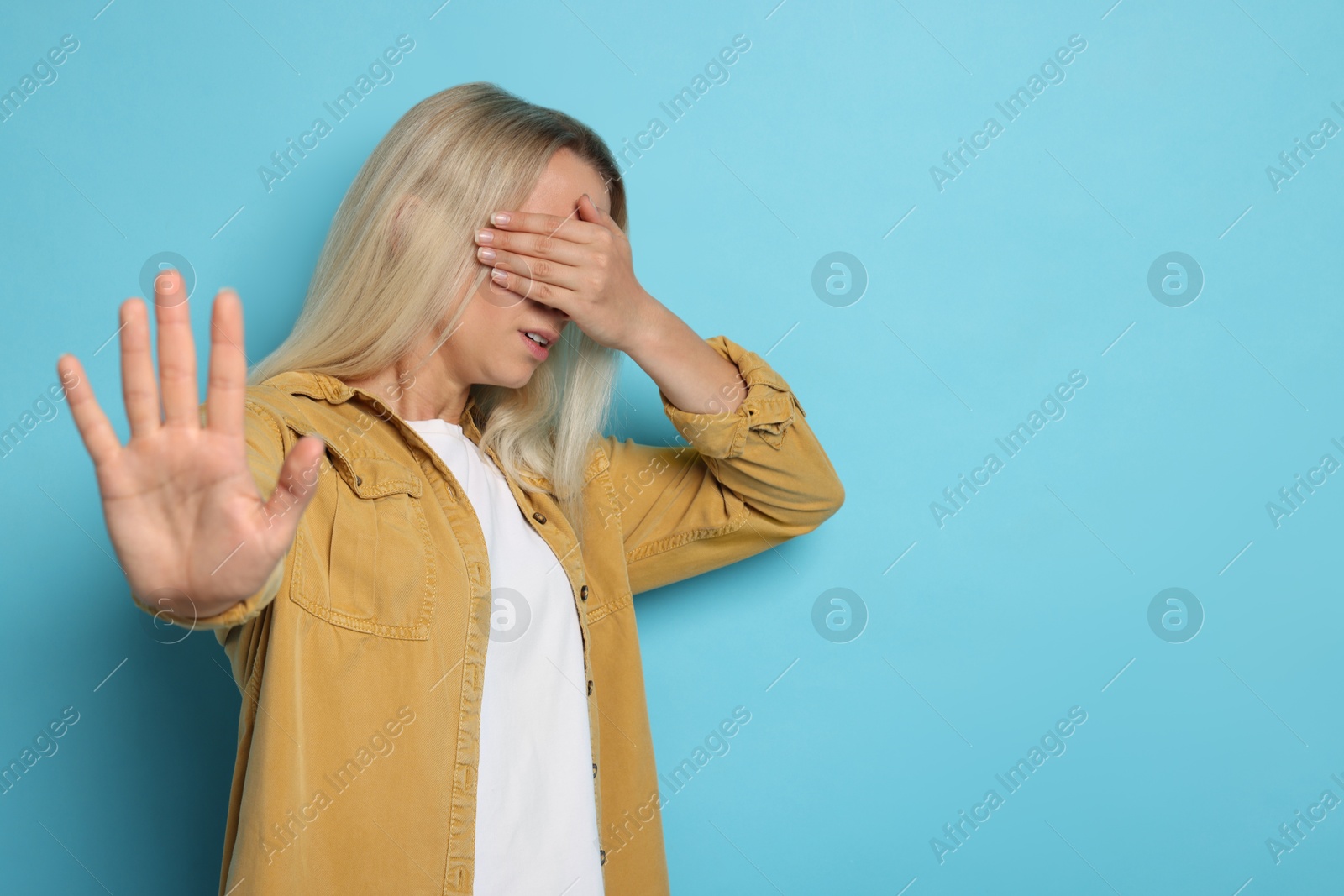 Photo of Portrait of scared woman on light blue background, space for text