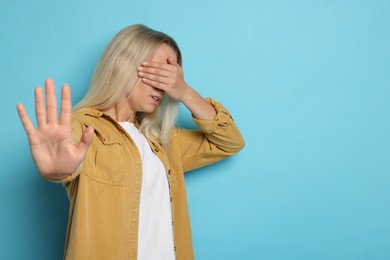 Photo of Portrait of scared woman on light blue background, space for text