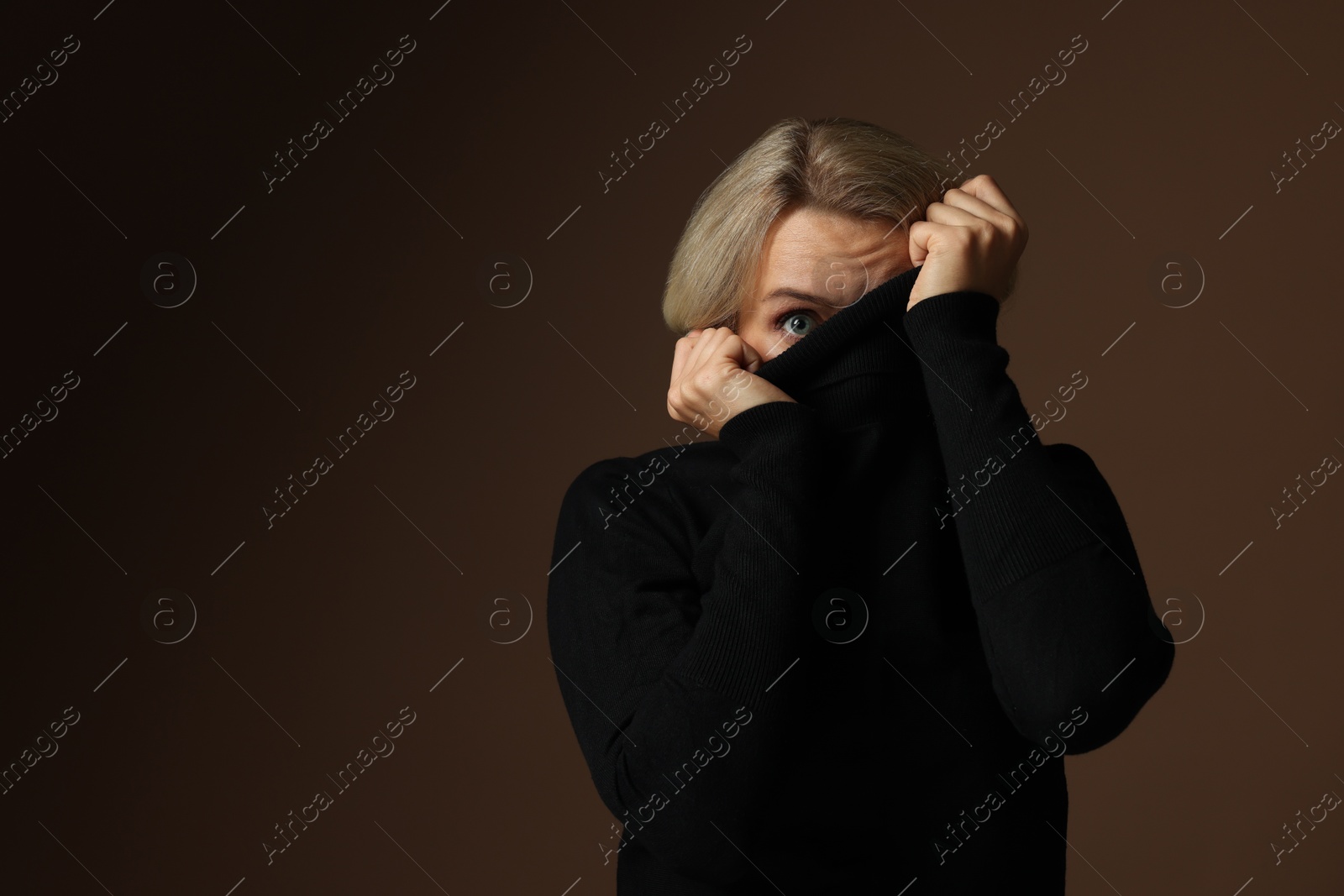 Photo of Portrait of scared woman on brown background, space for text