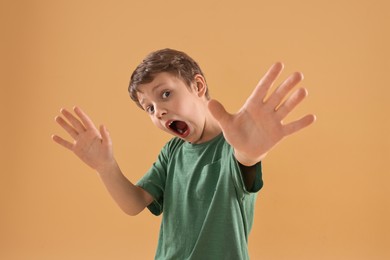 Portrait of scared little boy on beige background