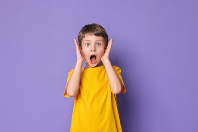 Portrait of scared little boy on violet background