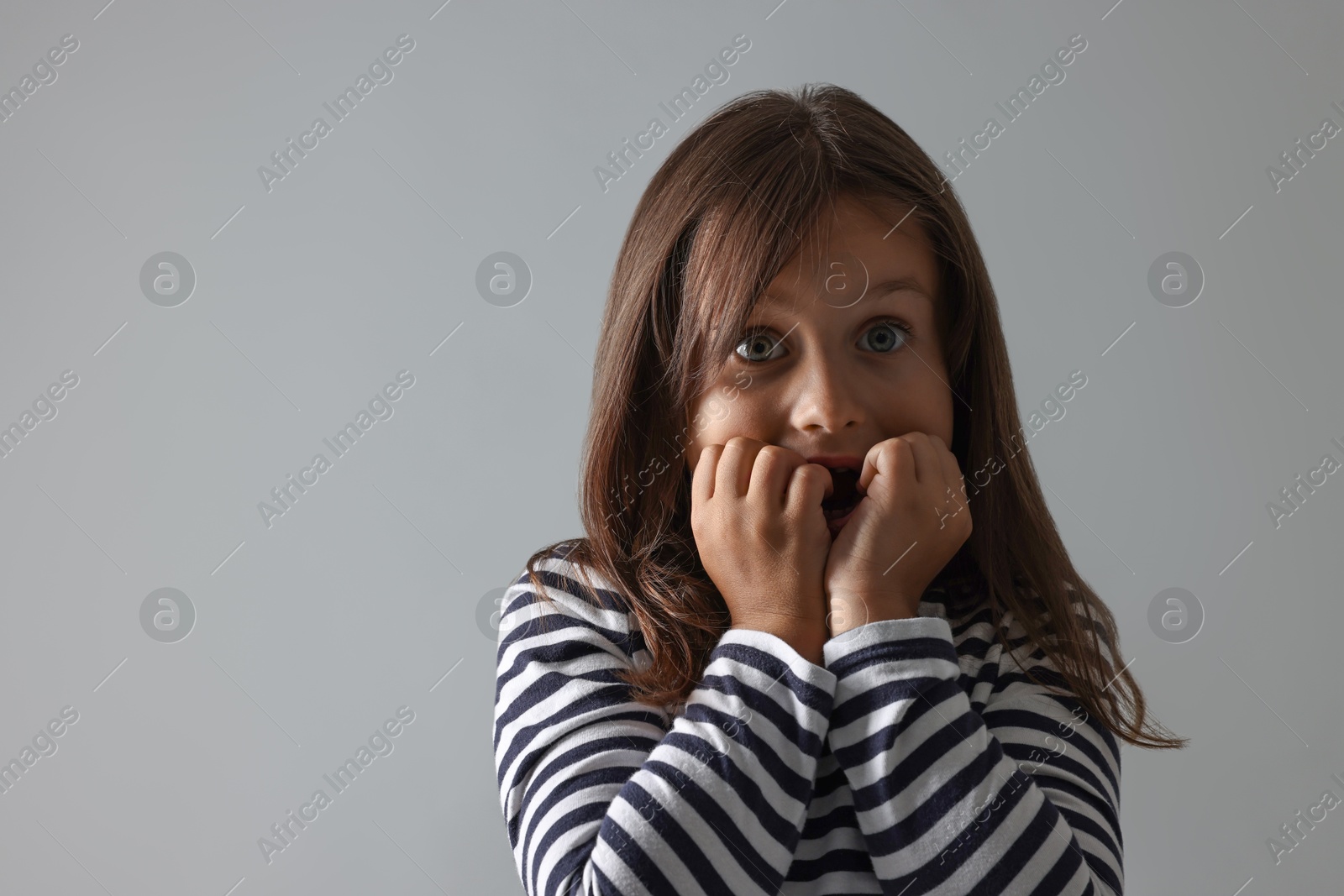 Photo of Scared little girl on grey background. Space for text