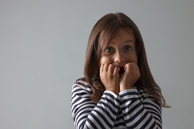 Photo of Scared little girl on grey background. Space for text