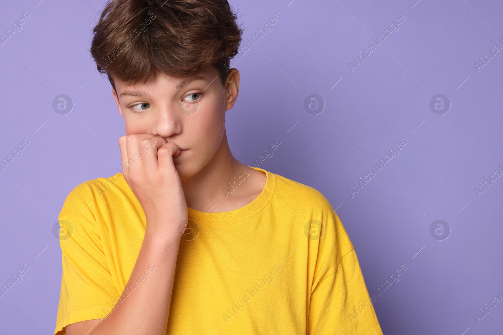 Photo of Scared teenage boy on violet background. Space for text