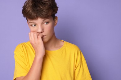 Scared teenage boy on violet background. Space for text