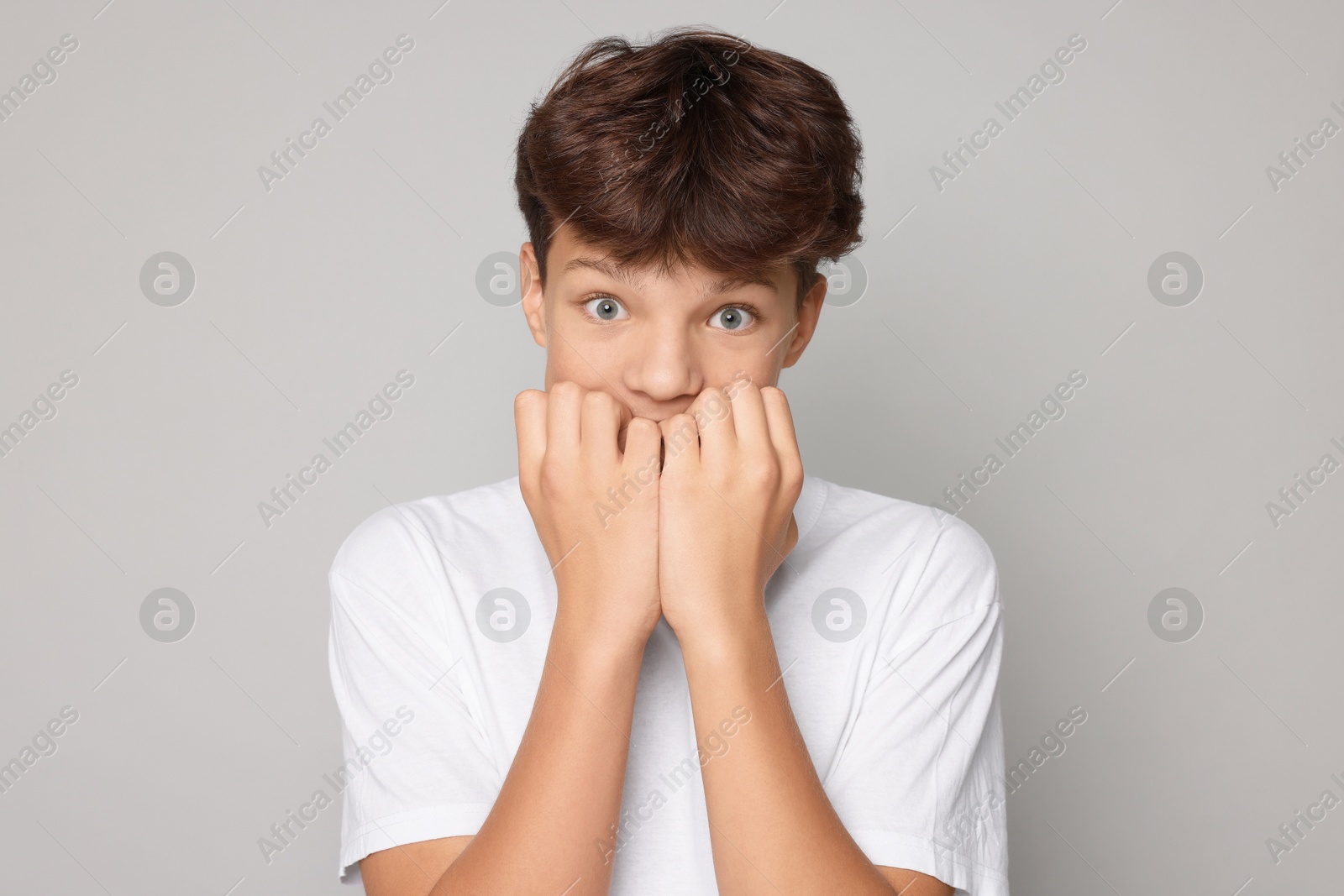 Photo of Portrait of scared teenage boy on grey background