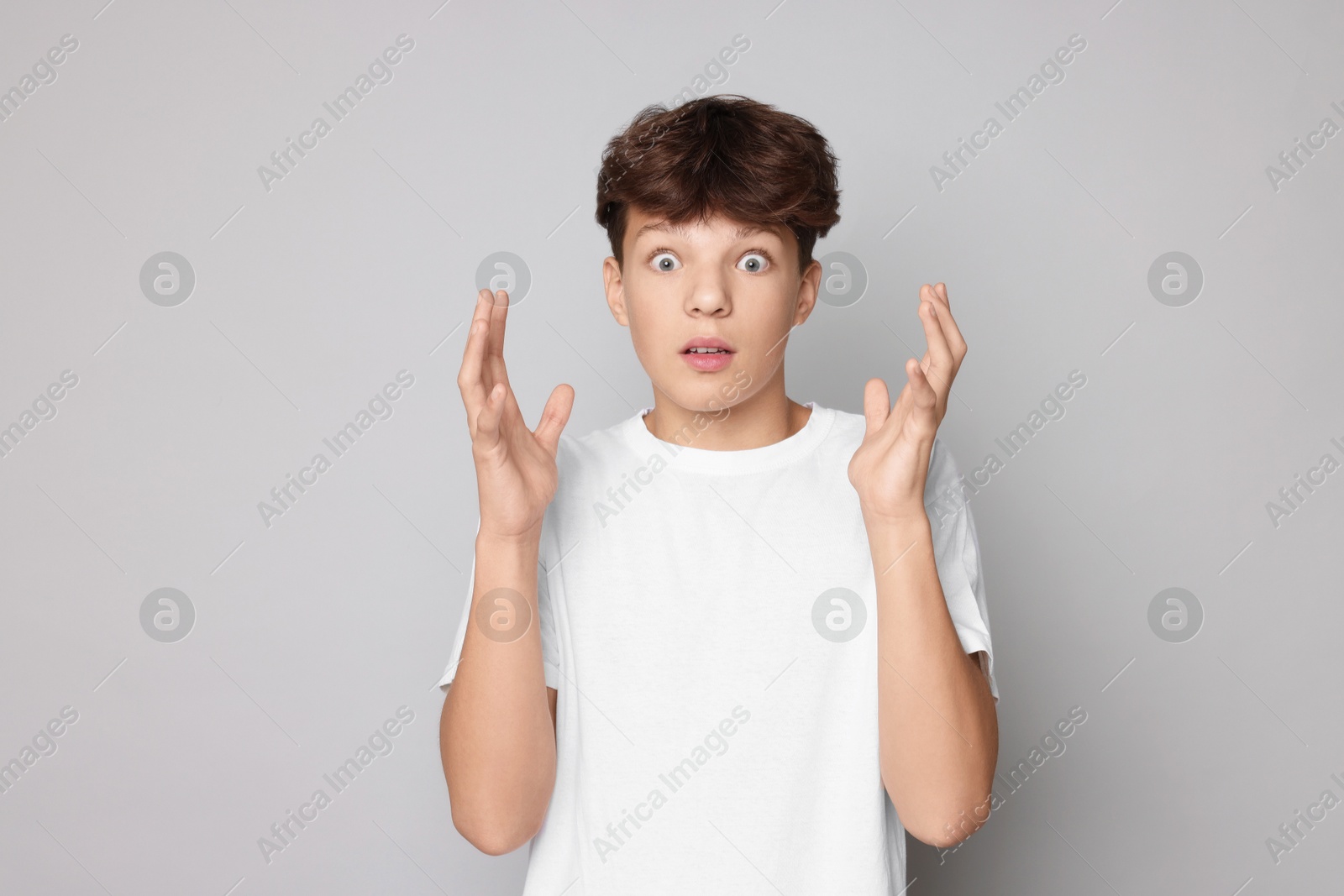 Photo of Portrait of scared teenage boy on grey background