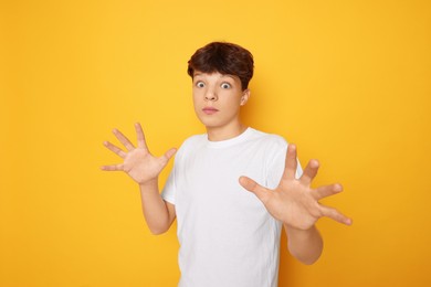 Photo of Portrait of scared teenage boy on orange background