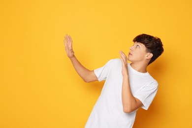 Photo of Scared teenage boy on orange background. Space for text