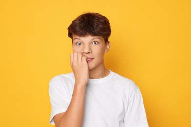 Photo of Portrait of scared teenage boy on orange background