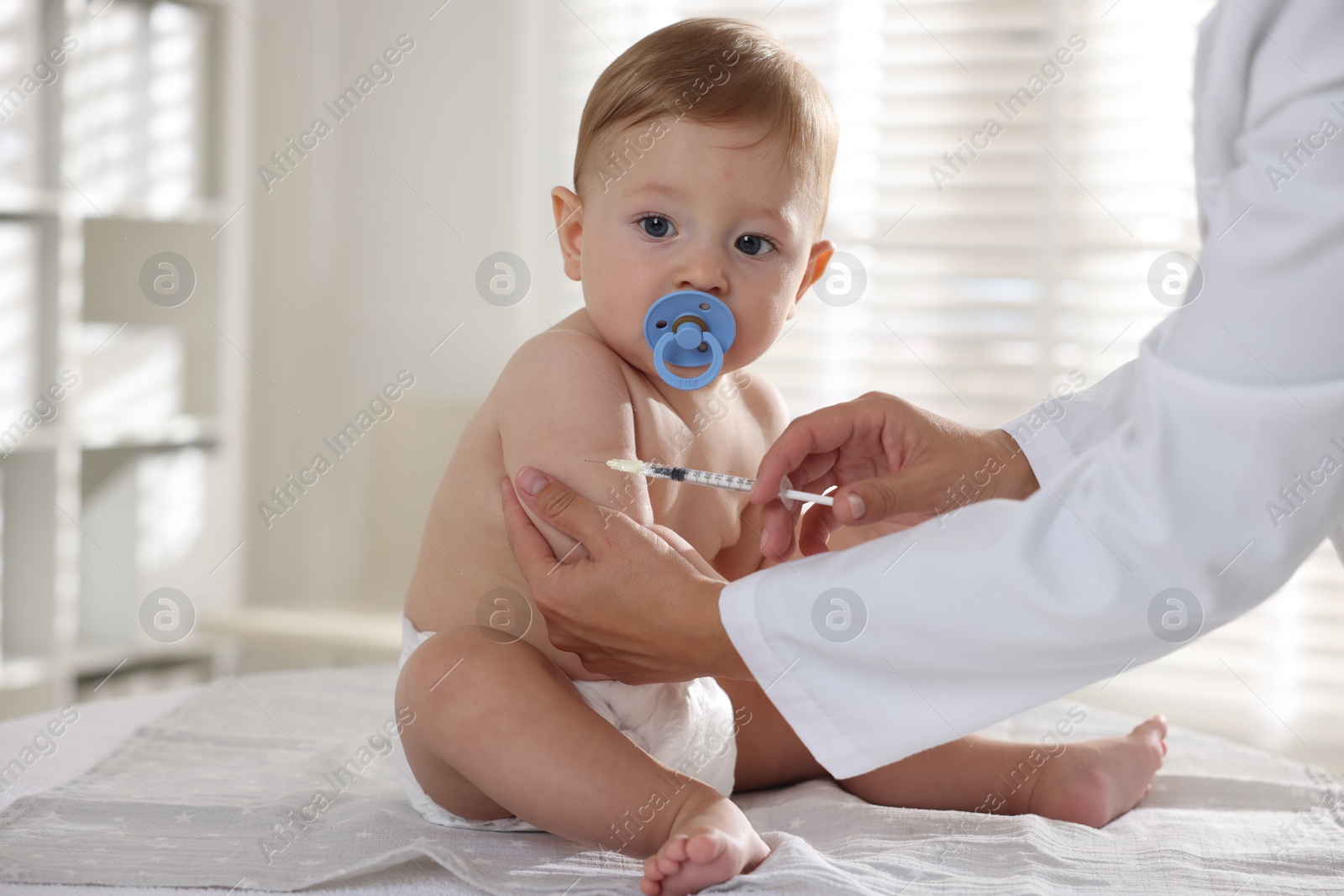 Photo of Pediatrician giving injection to cute baby in clinic, closeup