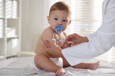 Pediatrician giving injection to cute baby in clinic, closeup