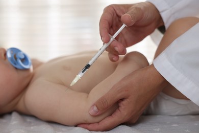 Pediatrician giving injection to baby in clinic, closeup