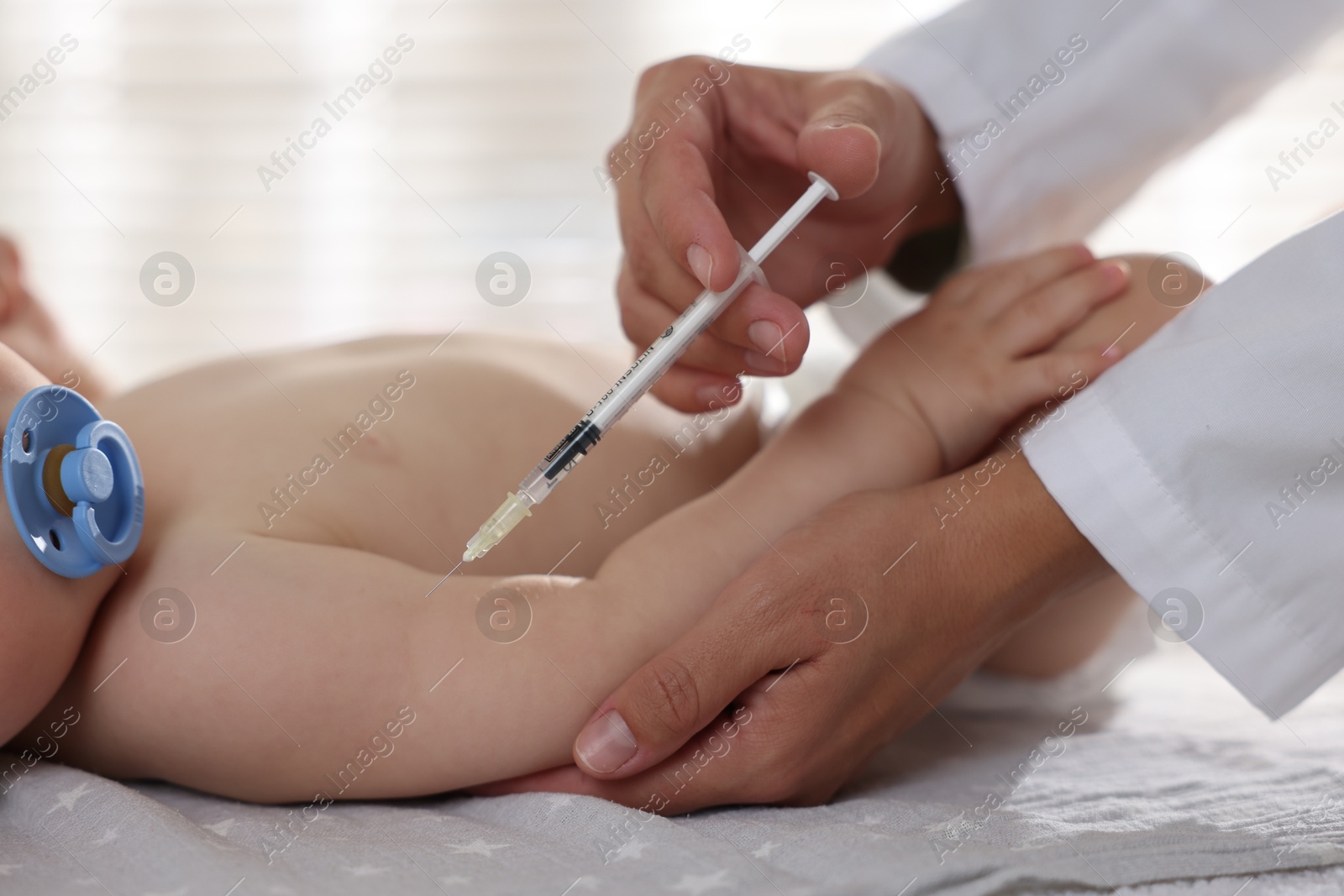 Photo of Pediatrician giving injection to baby in clinic, closeup