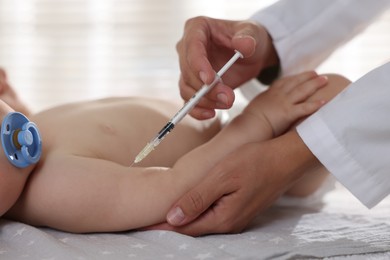 Pediatrician giving injection to baby in clinic, closeup