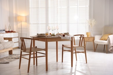 Photo of Stylish table setting with beautiful dishware and autumn decor in dining room