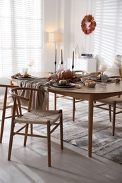 Stylish table setting with beautiful dishware and autumn decor in dining room