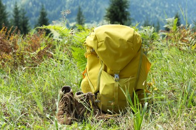 Backpack and trekking shoes on green grass outdoors