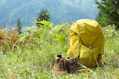 Photo of Backpack and trekking shoes on green grass outdoors