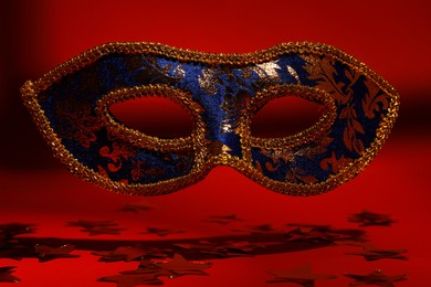 Photo of Beautiful blue carnival mask on red background