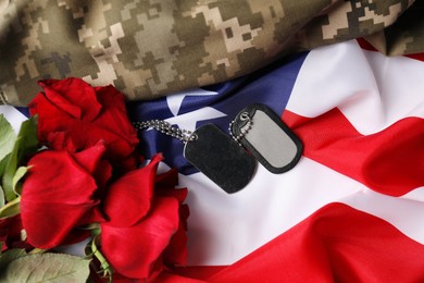 Photo of Veterans day. Army tokens, roses and military uniform on American flag, flat lay