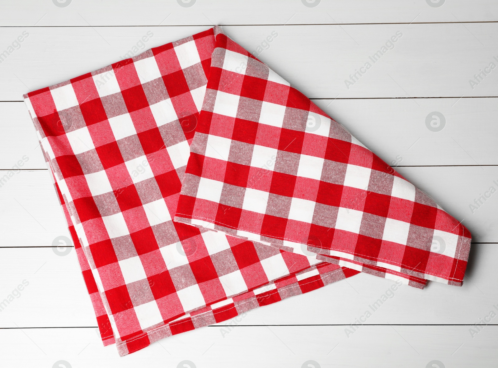 Photo of Folded tablecloth with checkered pattern on white wooden table, top view