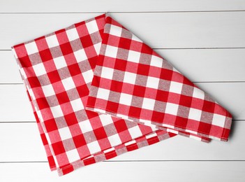 Folded tablecloth with checkered pattern on white wooden table, top view