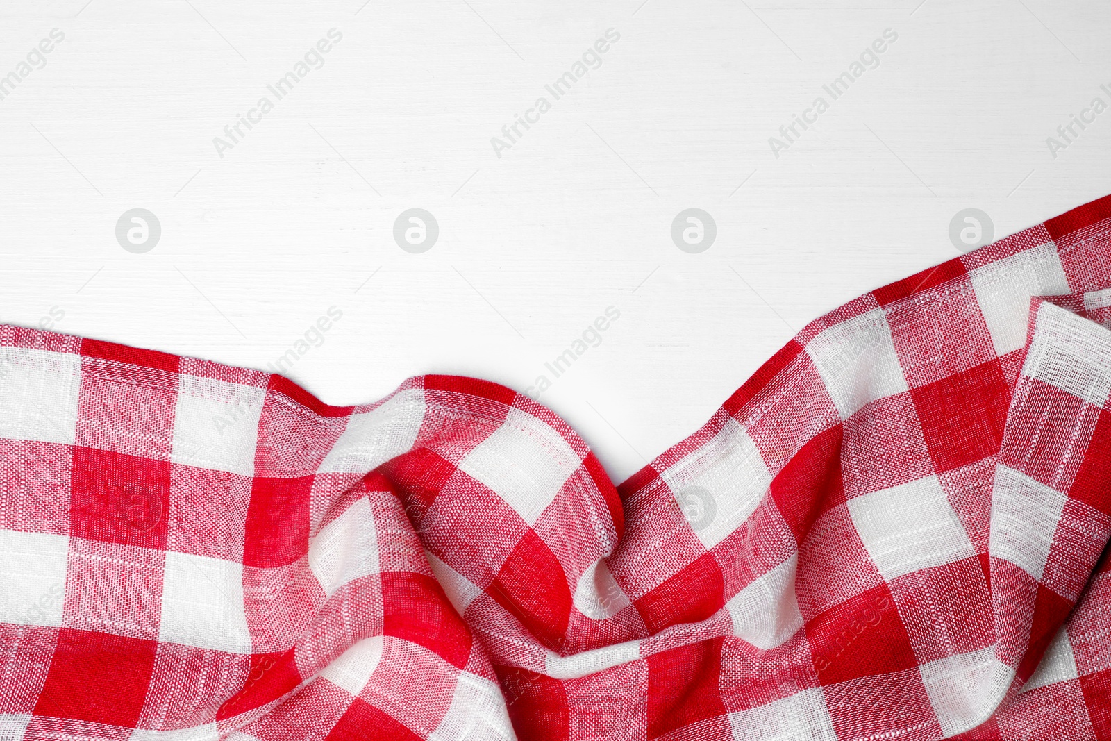 Photo of Crumpled tablecloth with checkered pattern on white wooden table, top view. Space for text