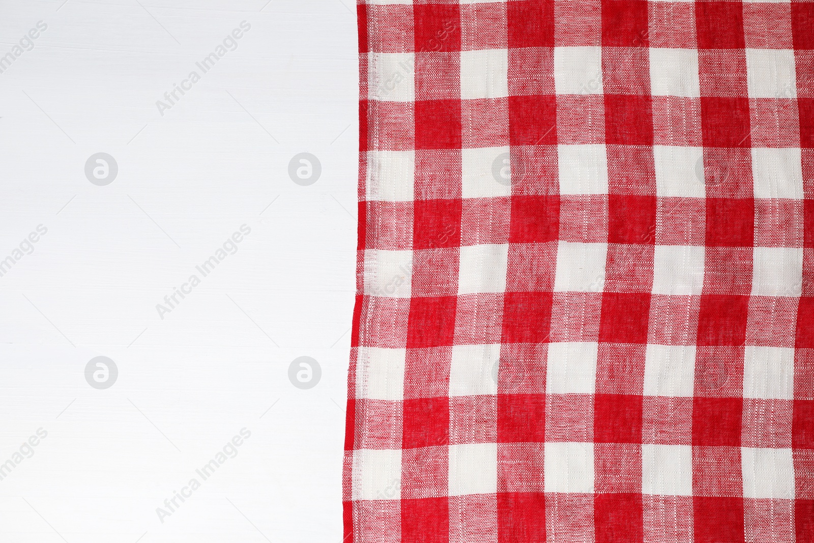 Photo of Tablecloth with checkered pattern on white wooden table, top view. Space for text