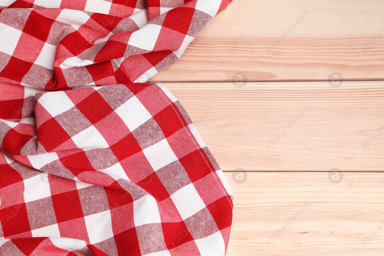 Photo of Crumpled tablecloth with checkered pattern on light wooden table, space for text