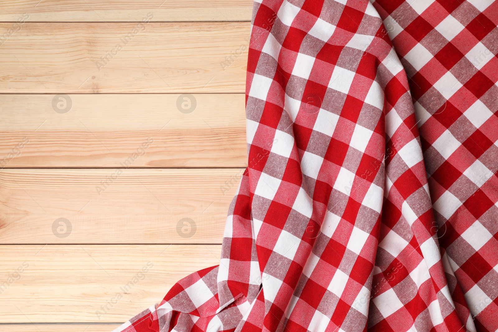 Photo of Crumpled tablecloth with checkered pattern on light wooden table, top view. Space for text