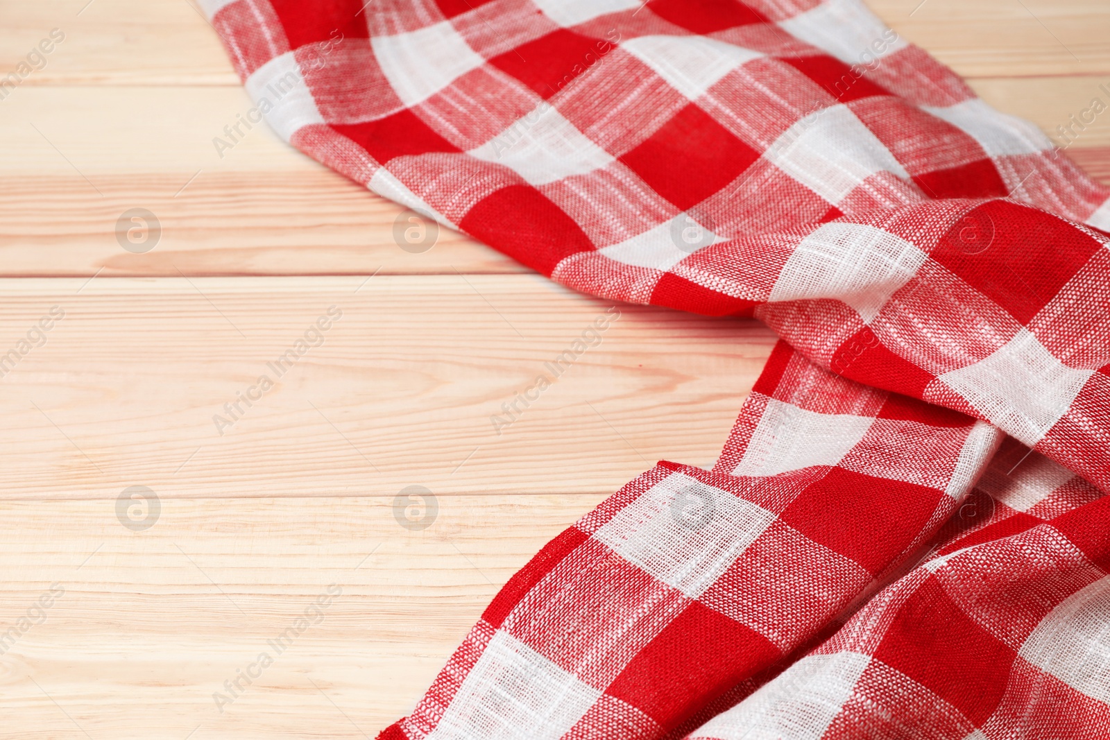 Photo of Crumpled tablecloth with checkered pattern on light wooden table, space for text