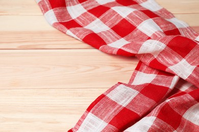 Crumpled tablecloth with checkered pattern on light wooden table, space for text