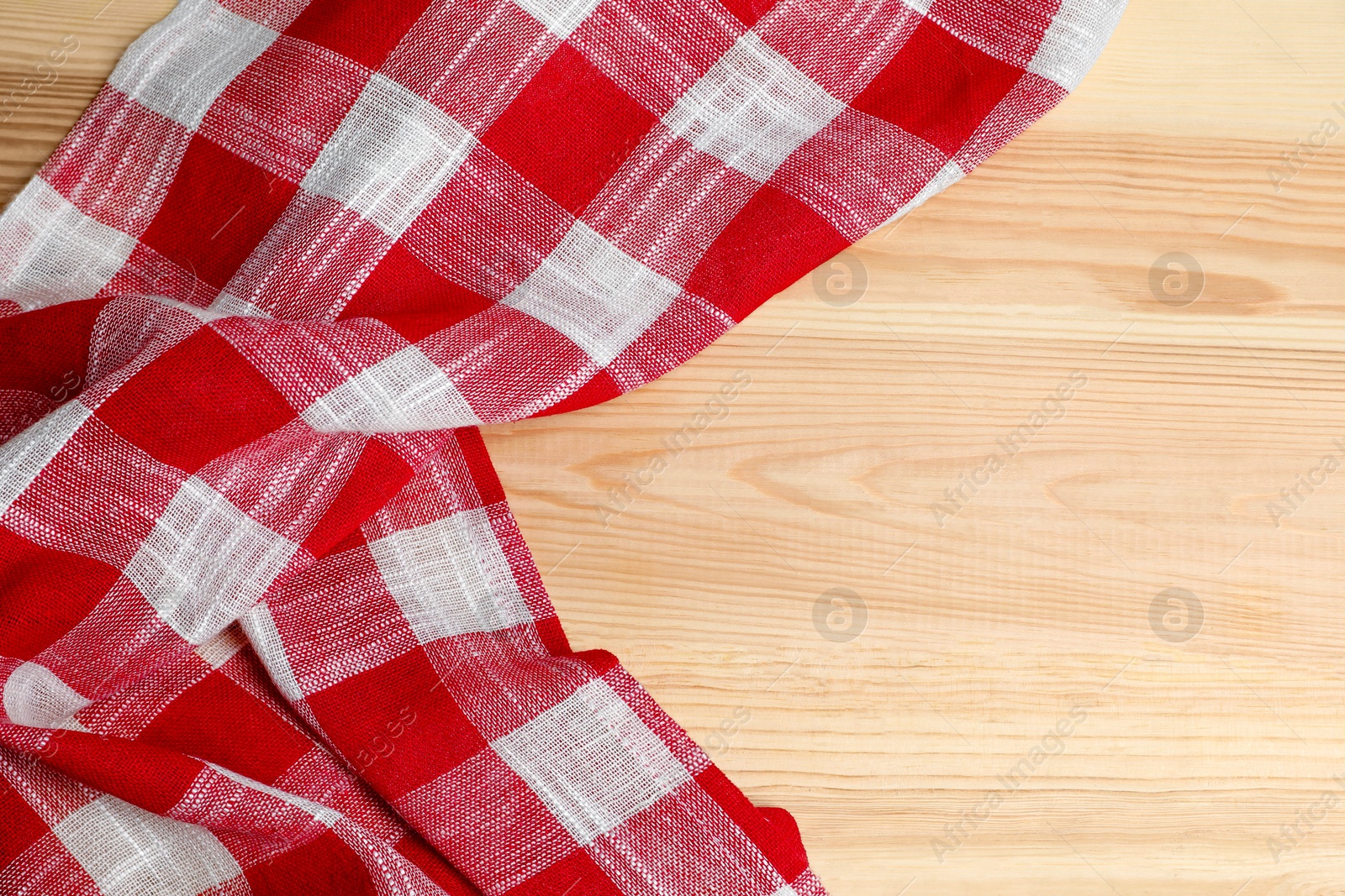 Photo of Crumpled tablecloth with checkered pattern on light wooden table, top view. Space for text