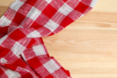 Photo of Crumpled tablecloth with checkered pattern on light wooden table, top view. Space for text