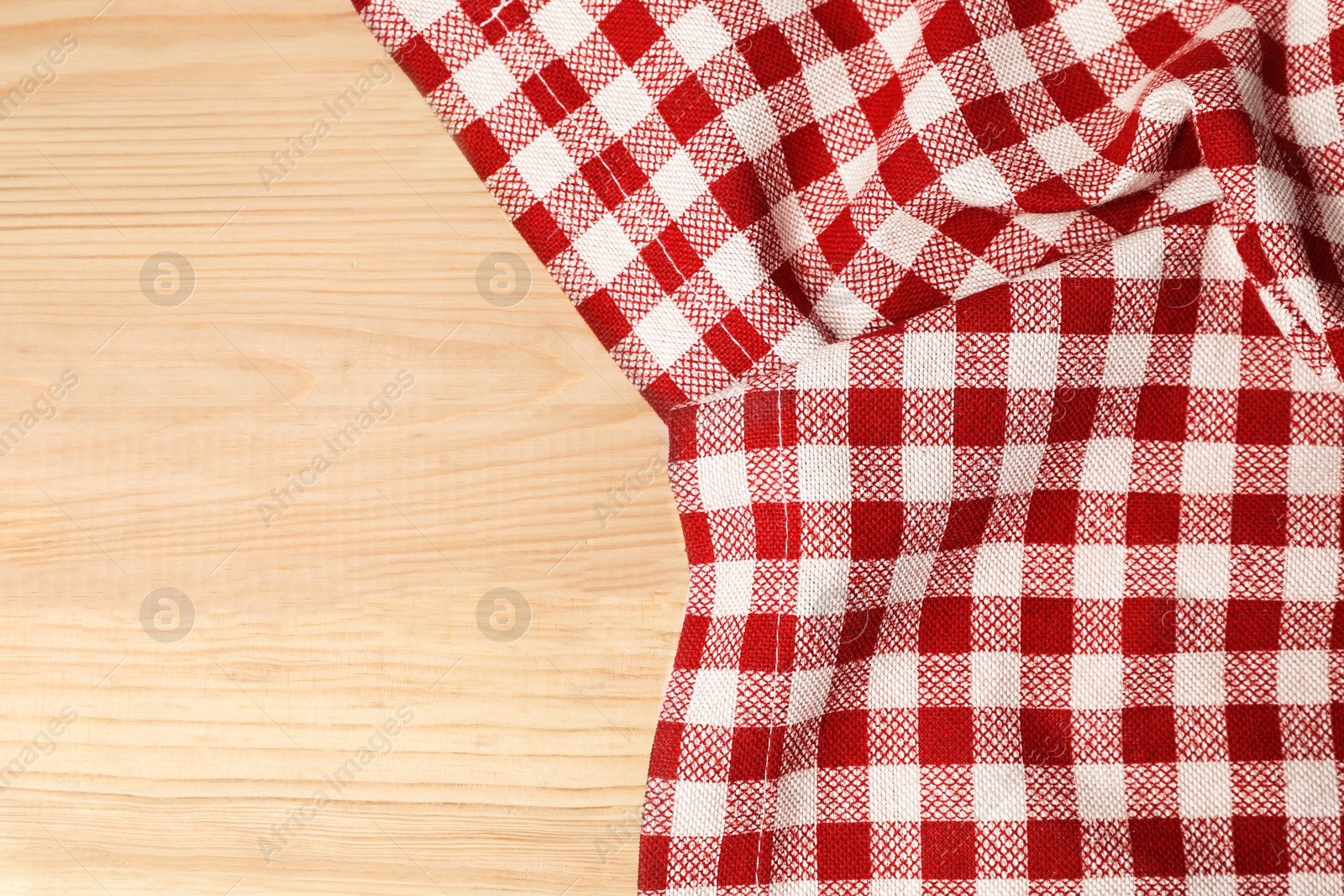 Photo of Crumpled tablecloth with checkered pattern on light wooden table, top view. Space for text