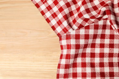 Crumpled tablecloth with checkered pattern on light wooden table, top view. Space for text