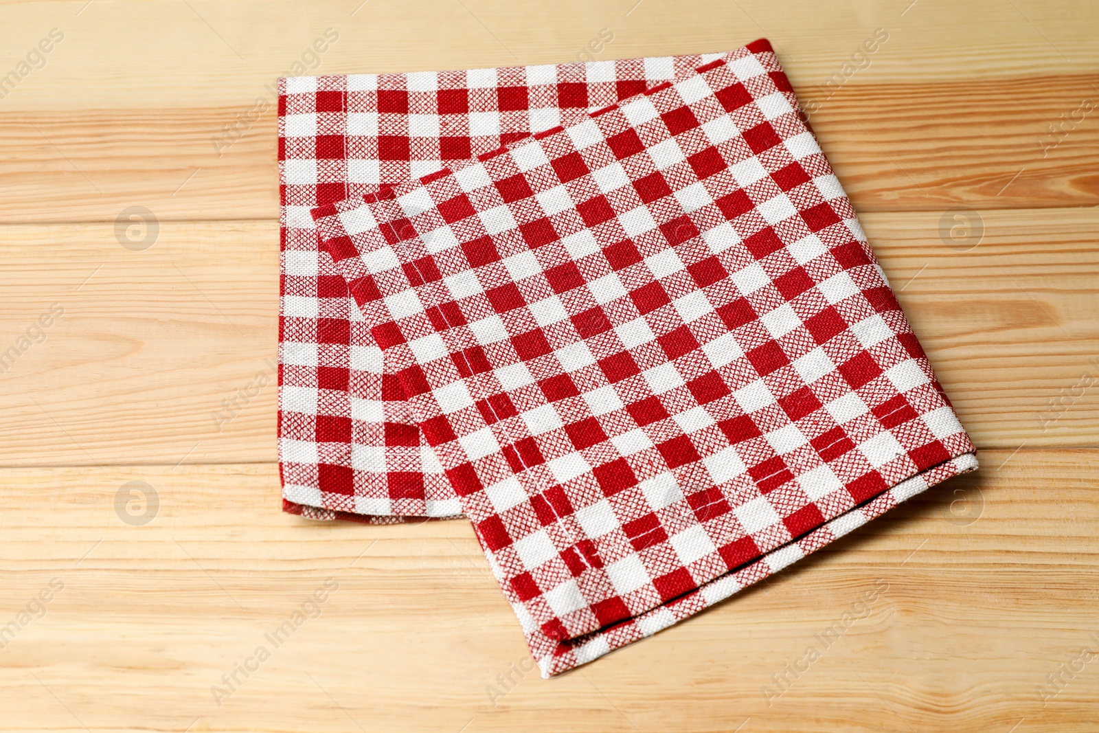 Photo of Folded tablecloth with checkered pattern on light wooden table, top view